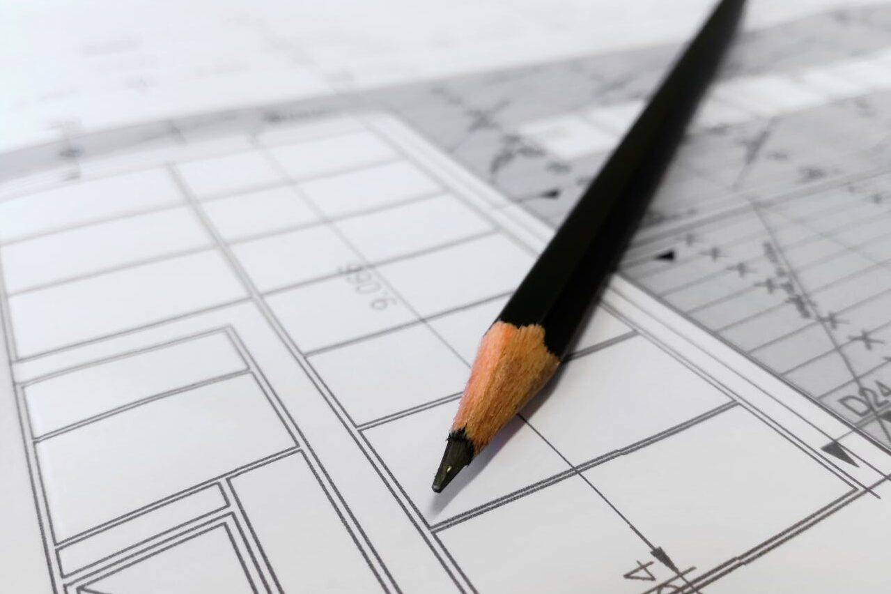 Detailed image of a black pencil resting on architectural blueprints, ideal for design and planning themes.